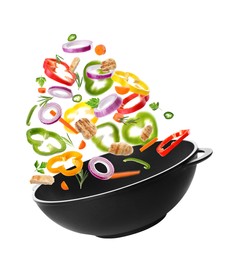 Different tasty ingredients falling into wok on white background