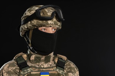Photo of Soldier in Ukrainian military uniform, tactical goggles and balaclava on black background. Space for text