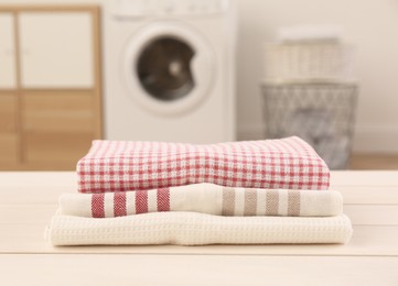 Stack of clean kitchen towels on white wooden table in laundry room