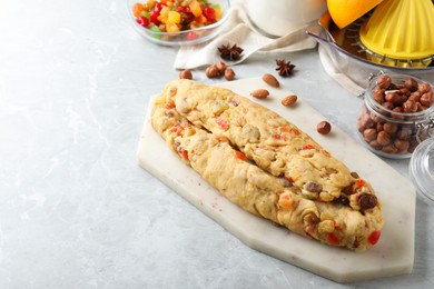 Unbaked Stollen with candied fruits and raisins on light marble table. Space for text