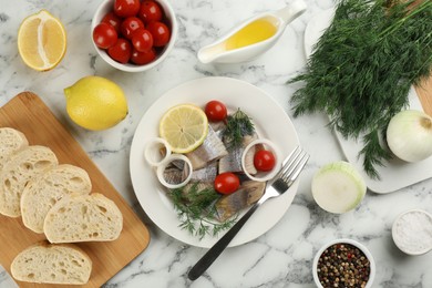 Photo of Sliced salted herring fillet served on white marble table, flat lay