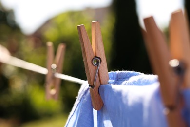 Photo of Clean clothes drying in garden, closeup. Focus on clothespin
