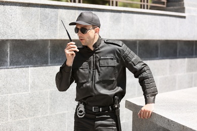 Male security guard using portable radio transmitter outdoors