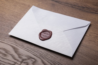 White envelope with wax seal on wooden table