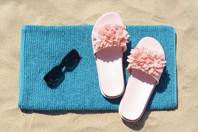 Photo of Towel, flip flops and sunglasses on sand, top view. Beach accessories