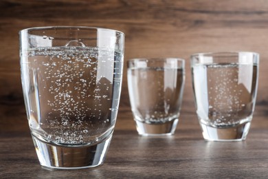 Glasses of soda water on wooden table, closeup