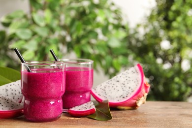Delicious pitahaya smoothie and fresh fruits on wooden table, space for text