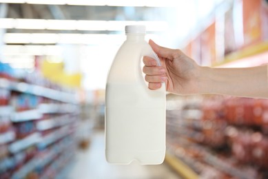 Woman holding gallon bottle of milk in supermarket, closeup