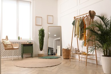 Photo of Modern room with clothes rack and big mirror. Interior design