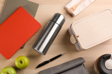 Flat lay composition with thermos and lunch box on wooden background