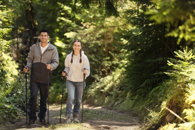 Couple with trekking poles hiking in forest