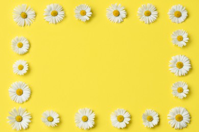 Frame of daisy flowers on yellow background, flat lay. Space for text