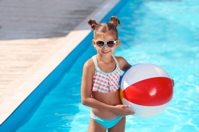 Cute little girl with inflatable ball in swimming pool