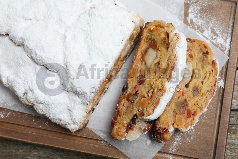 Traditional Christmas Stollen with icing sugar on wooden board, top view