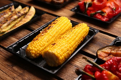 Plastic containers with different grilled meal on wooden table, closeup. Food delivery service