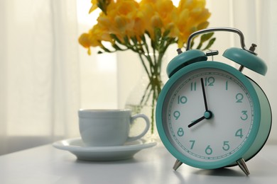 Alarm clock on white table indoors, space for text. Morning time