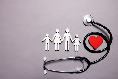 Photo of Figures of family near stethoscope and heart on lilac background, top view. Insurance concept