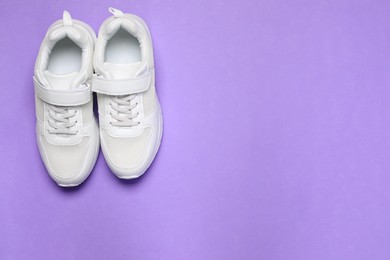 Pair of comfortable sports shoes on violet background, flat lay. Space for text