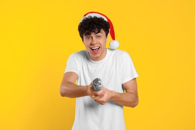 Photo of Emotional young man in santa hat with party popper on orange background