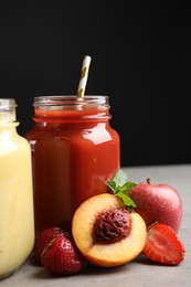 Photo of Delicious juices and fresh ingredients on grey table against black background