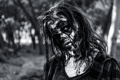 Photo of Scary zombie outdoors, black and white effect. Halloween monster