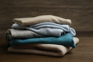 Photo of Stack of cashmere clothes on wooden background