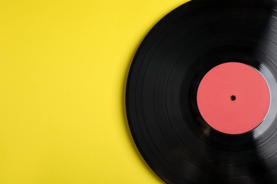 Vintage vinyl record on yellow background, top view. Space for text