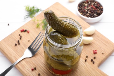 Tasty pickled cucumbers in jar on wooden board, closeup