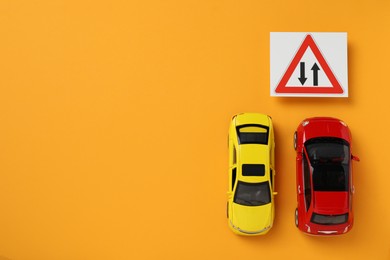 Toy cars and road sign Two Way Direction on yellow background, flat lay. Space for text