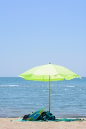Light green beach umbrella in sand near sea on sunny day