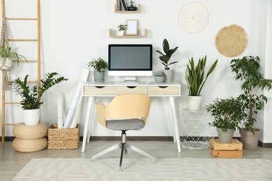Photo of Comfortable workplace with modern computer and different houseplants in room