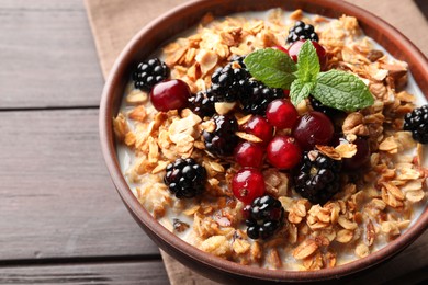 Bowl of muesli served with berries and milk on wooden table, closeup
