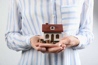 Woman holding house model and coins, closeup