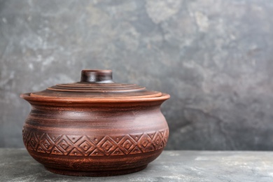 Clay pot on grey table, space for text. Handmade utensil