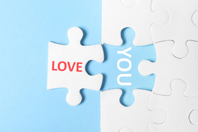 Puzzle with phrase LOVE YOU on light blue background, top view