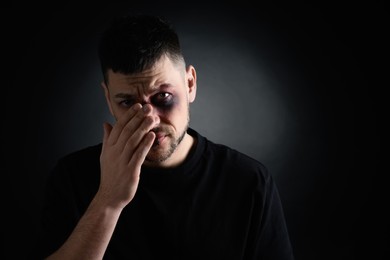 Man with facial injuries on dark background, space for text. Domestic violence victim