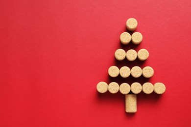 Photo of Christmas tree made of wine corks on red background, top view. Space for text