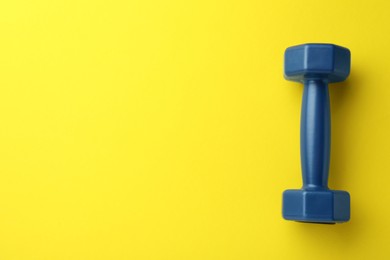 Stylish dumbbell on yellow background, top view. Space for text