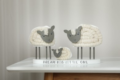 Photo of Cute decorative sheep and lamb figurine with phrase Dream Big Little One on white table against light background. Family Day