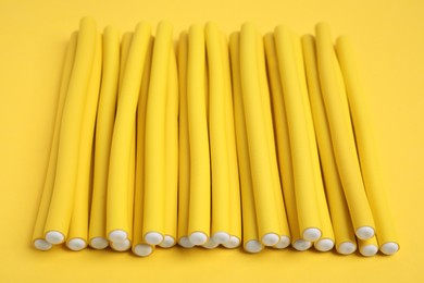 Curling rods on yellow background. Hair styling tool