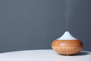 Aroma oil diffuser lamp on table against gray background. Space for text