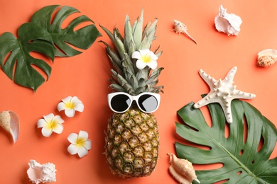 Flat lay composition with pineapple, sunglasses and beach items on orange background. Creative concept