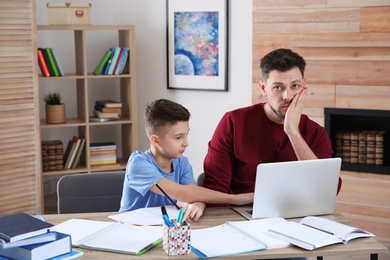 Dad helping his son with difficult homework assignment in room, space for text