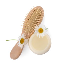 Solid shampoo bar, hairbrush and chamomiles on white background, top view. Hair care