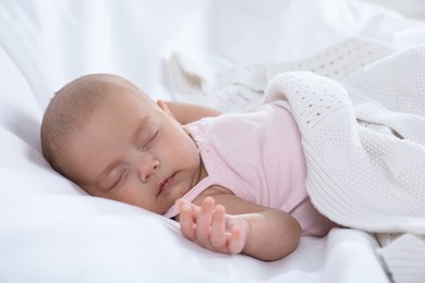 Cute little baby in bodysuit sleeping on bed