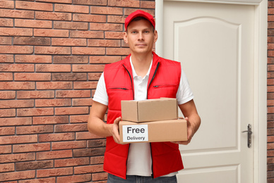Courier holding parcels with sticker Free Delivery indoors