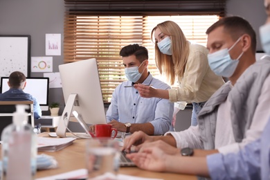 Coworkers with masks in office. Protective measure during COVID-19 pandemic