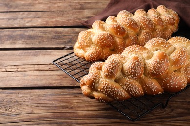 Homemade braided breads with sesame seeds on wooden table, space for text. Traditional Shabbat challah