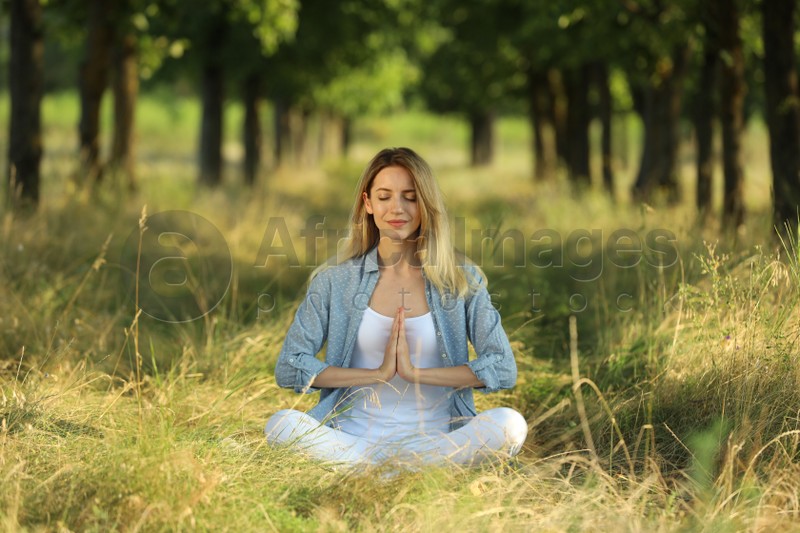 Photo of Young woman meditating in forest on sunny day