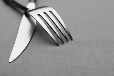 Shiny fork and knife on grey table, closeup
